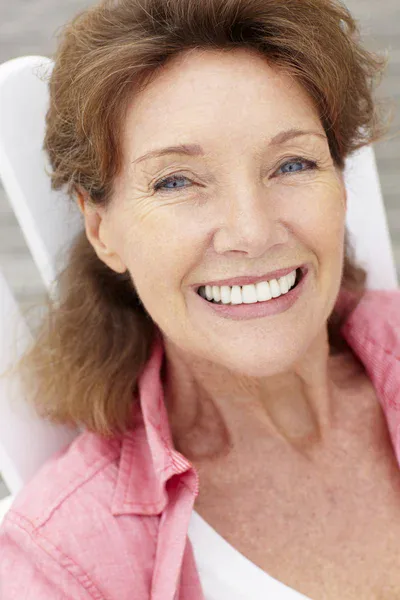 Close-up portrait of a smiling mature woman with healthy skin, symbolizing vitality and balanced body wellness.